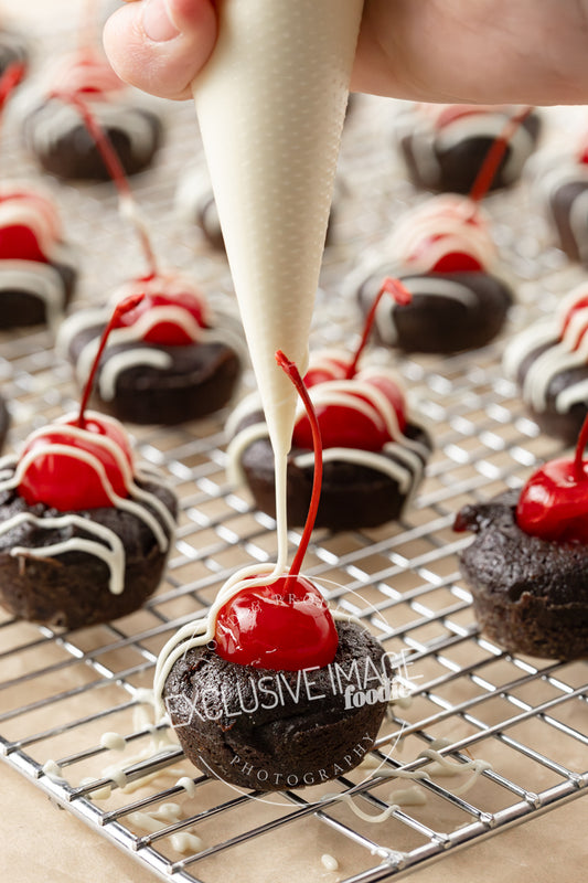 chocolate brownie bites with white chocolate being drizzled over the top