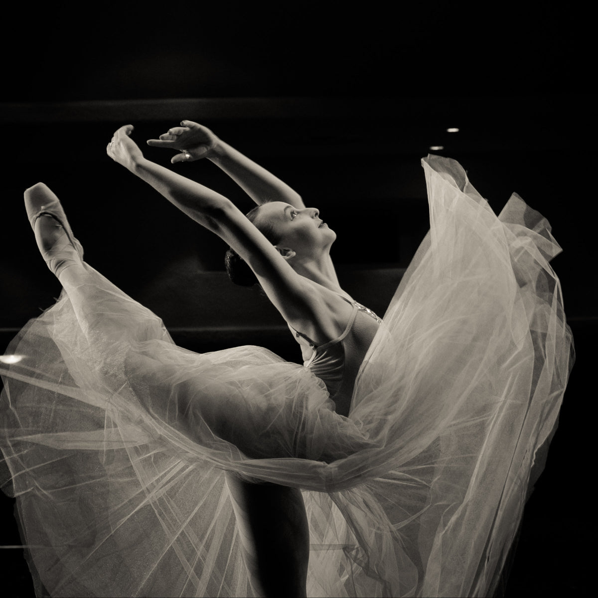 Ballet dancer with flowing white tutu against a dark background