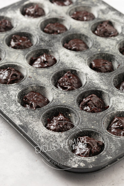 Muffin tin with brownie batter in each cup on a white background
