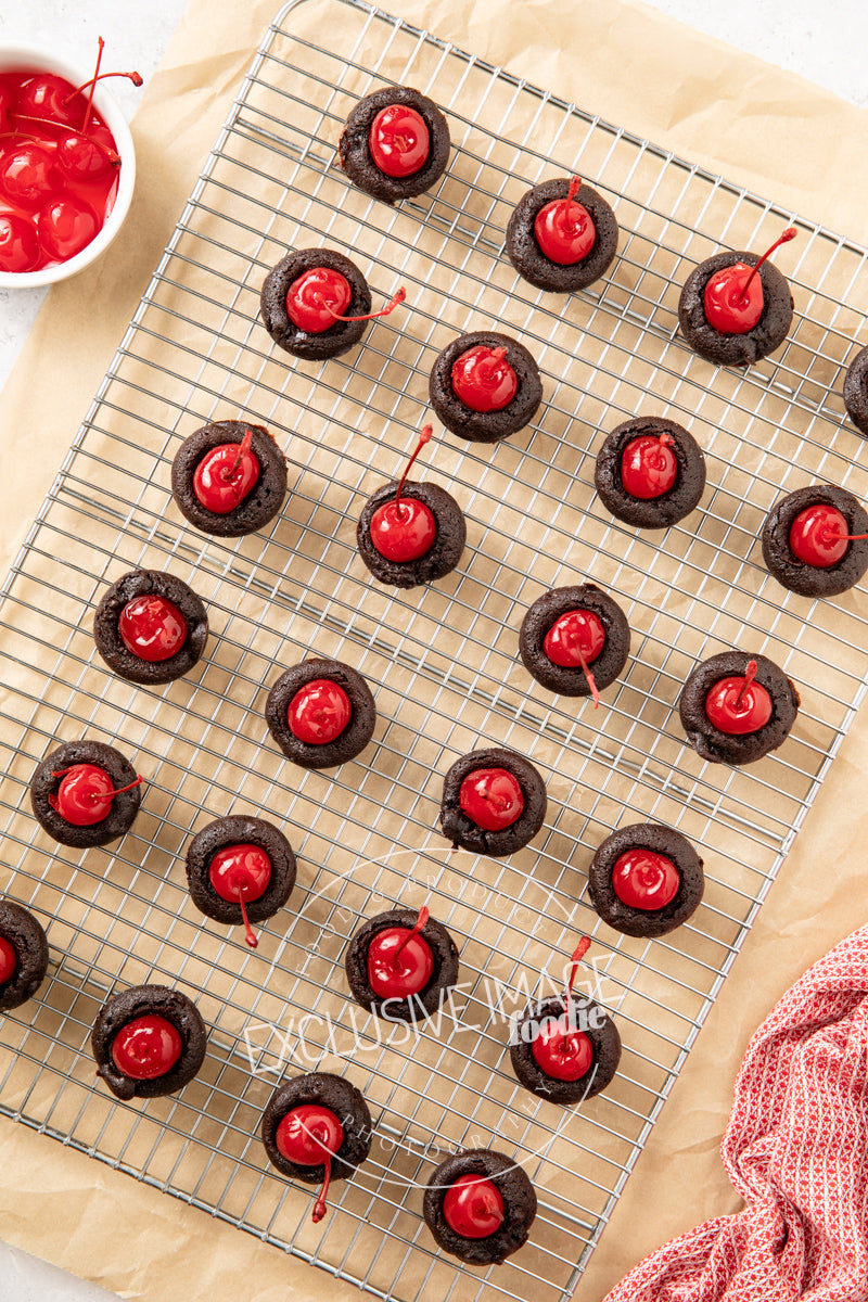 Chocolate 2 bite brownies with red cherries on a cooling rack