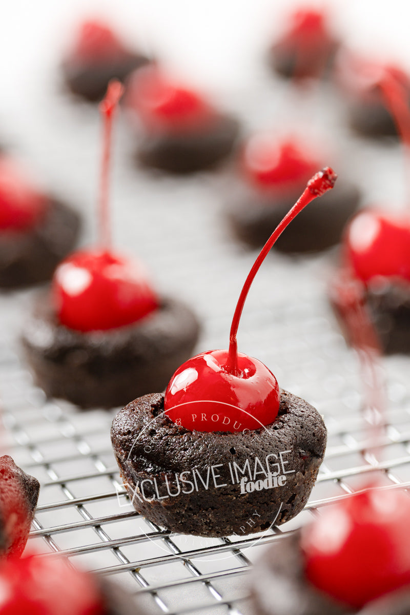 Chocolate brownie bites with red cherries on a cooling rack