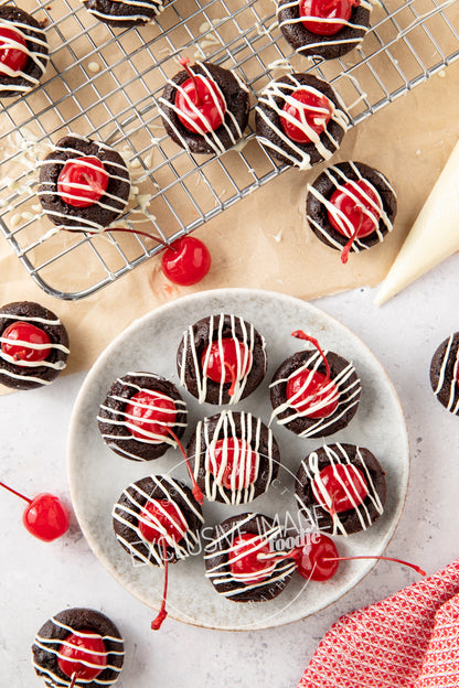 Chocolate brownies with cherries on a plate and cooling rack.