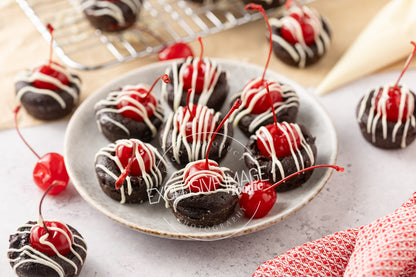 Brownie bites with cherries on a plate, placed on a light surface.