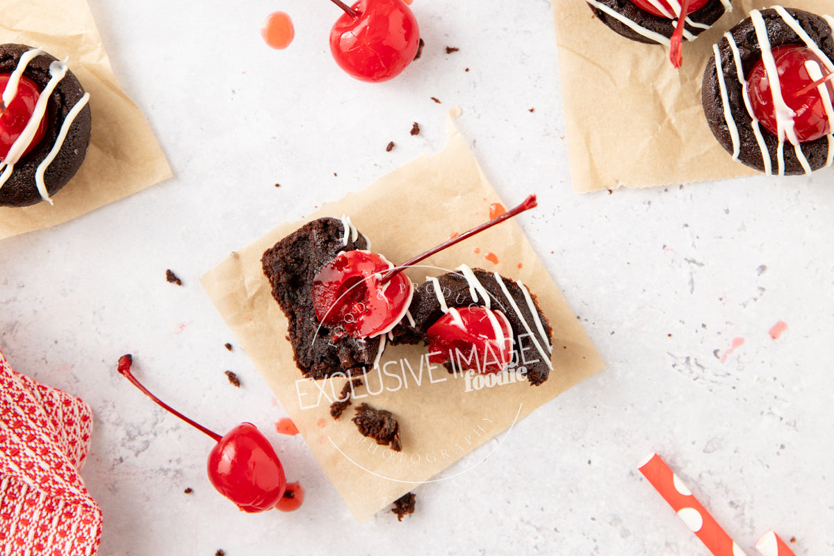 Chocolate brownie bites with cherries on a white surface