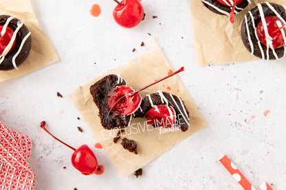 Chocolate brownie bites with cherries on a white surface