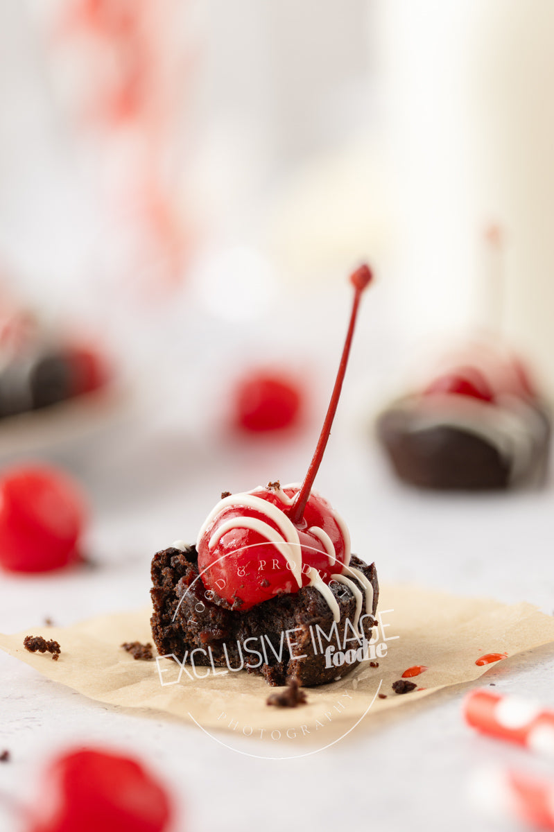 Chocolate brownie with a cherry on top on a white surface