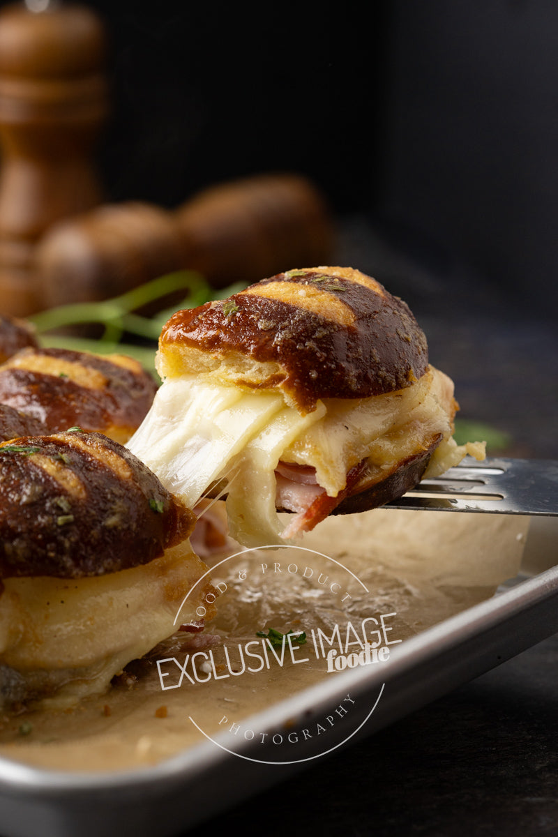 Close-up of a sandwich with melted cheese and bread on a plate, with a fork lifting a piece.