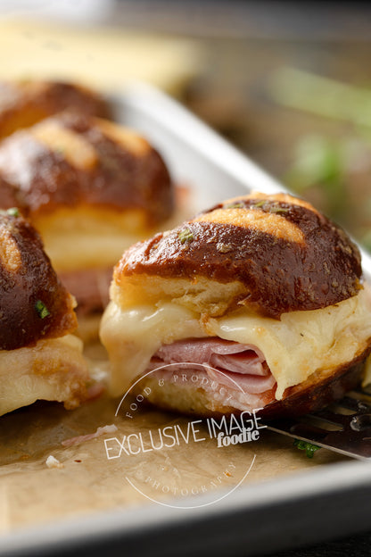 Close-up of a slider sandwich with melted cheese and ham on a bun, with 'Foodie' branding.