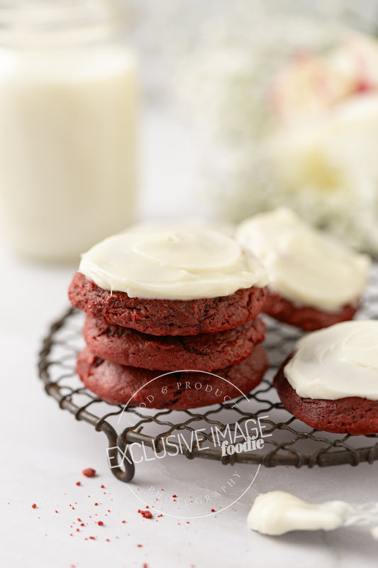 Red velvet cookies with cream cheese frosting on a cooling rack with a blurred background